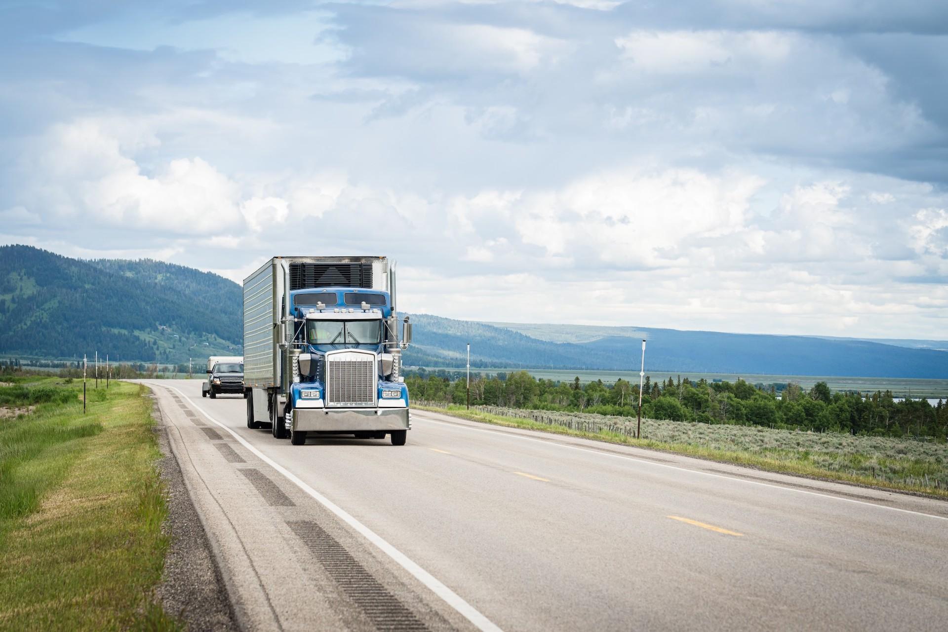 Oncoming semi-truck driving down a highway with hills in the background