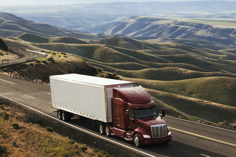 A commercial truck driving through the high rolling hills of southeastern Washington, USA