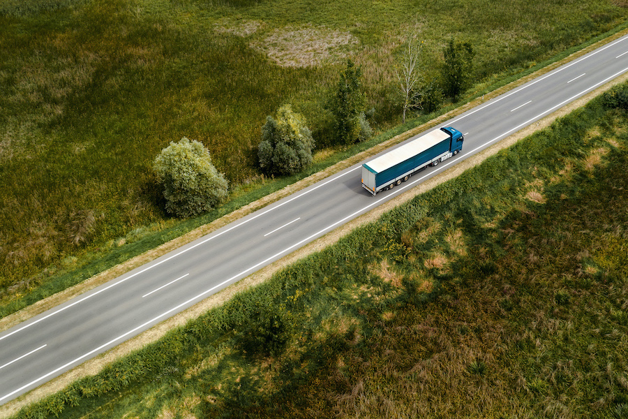 Large freight transporter semi-truck on the road, aerial view from drone pov